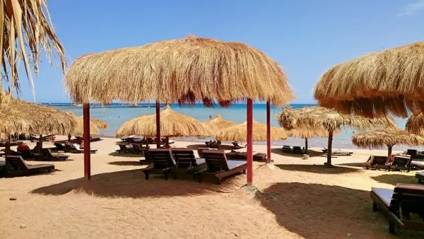 Słoneczna plaża z leżakami i parasolami z trawy. Idealne miejsce na relaks w stylu caves beach resort.