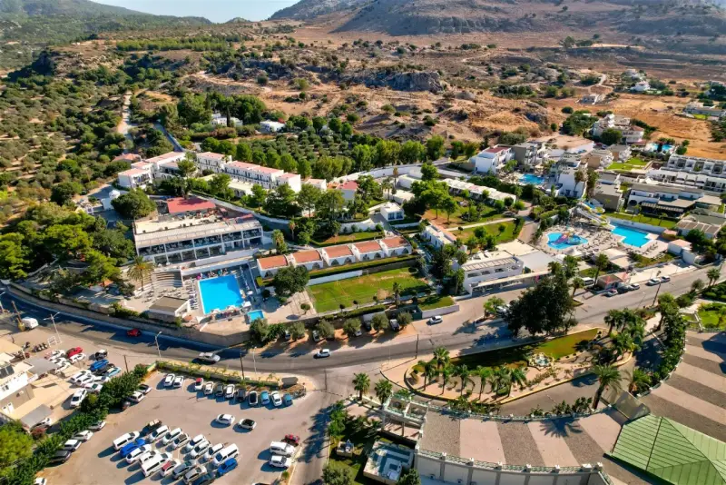 Widok z lotu ptaka na hotel Ellia Rodos z basenami, zjeżdżalniami i parkingiem pełnym samochodów.